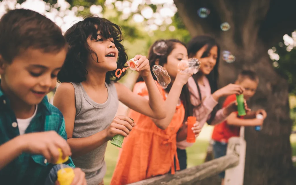 Kids blowing bubbles outside as a group.