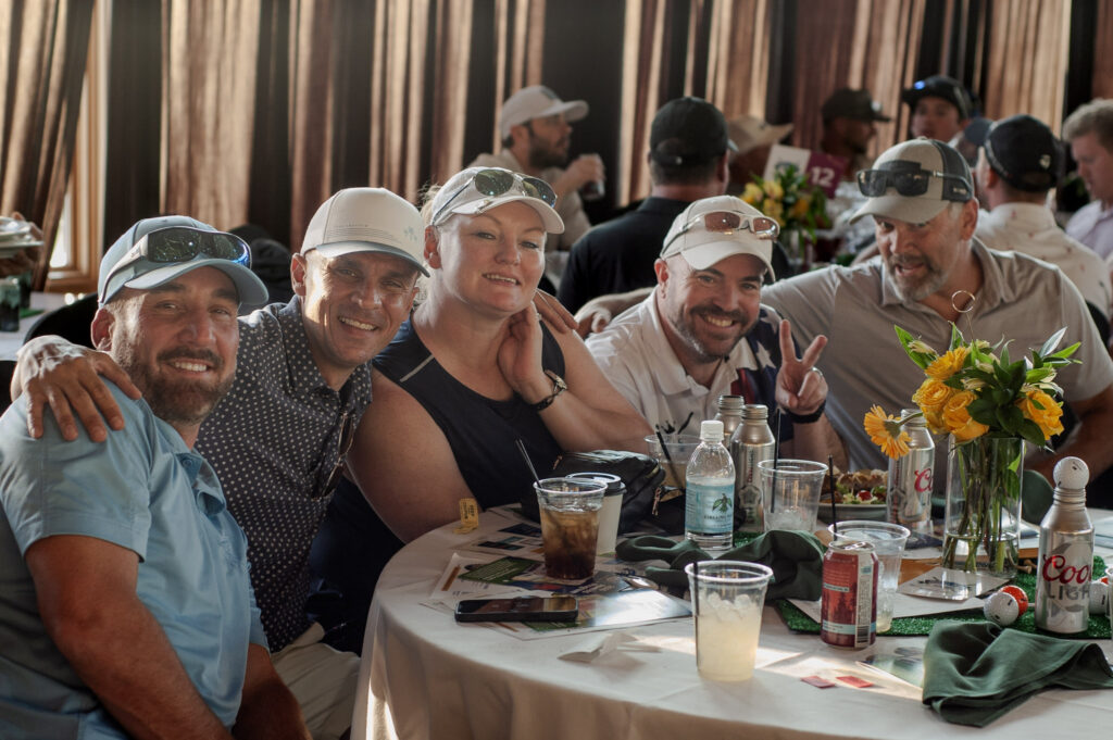 Golfers sharing a table at a past Believe in Me Circling Raven golf event