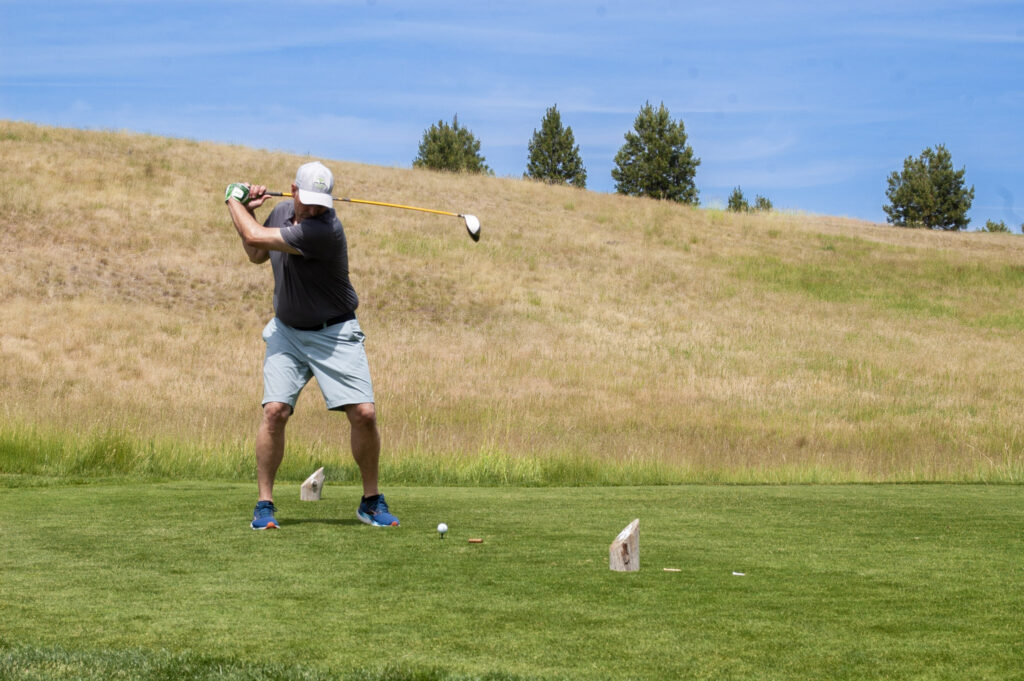 Golfer taking a swing on the Circling Raven course during a past Believe in Me tournament
