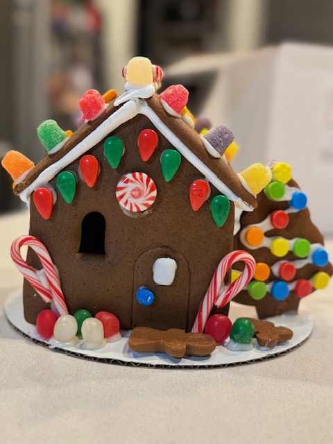A finished gingerbread house decorated with icing, gumdrops, and colorful candy.